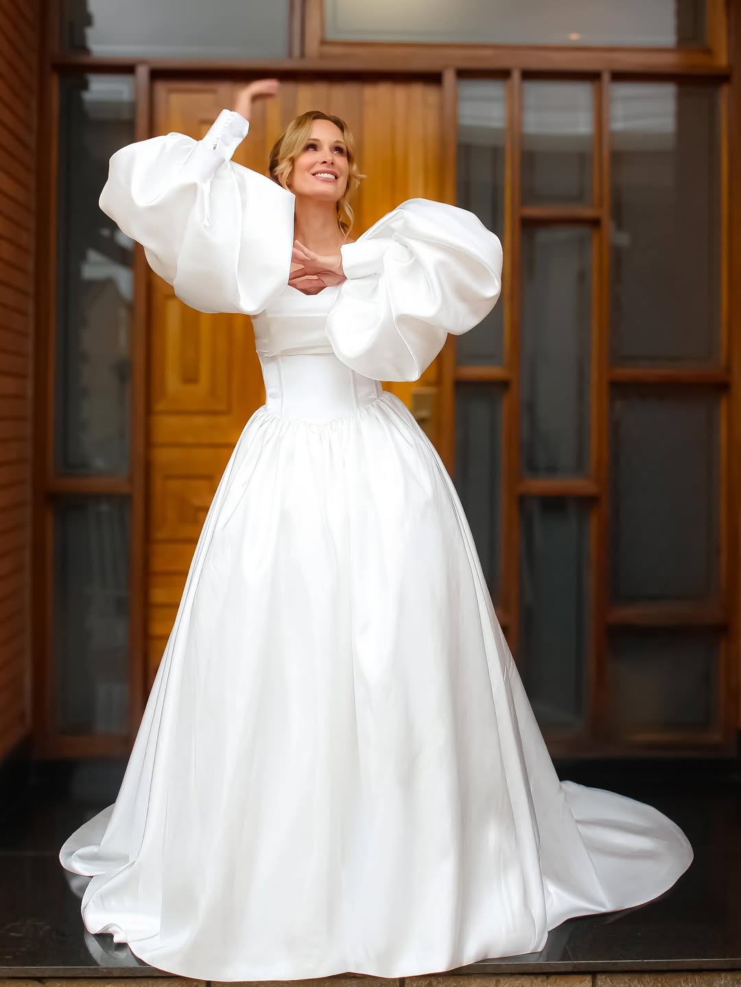 Vestido de mangas bufantes diante da porta de madeira